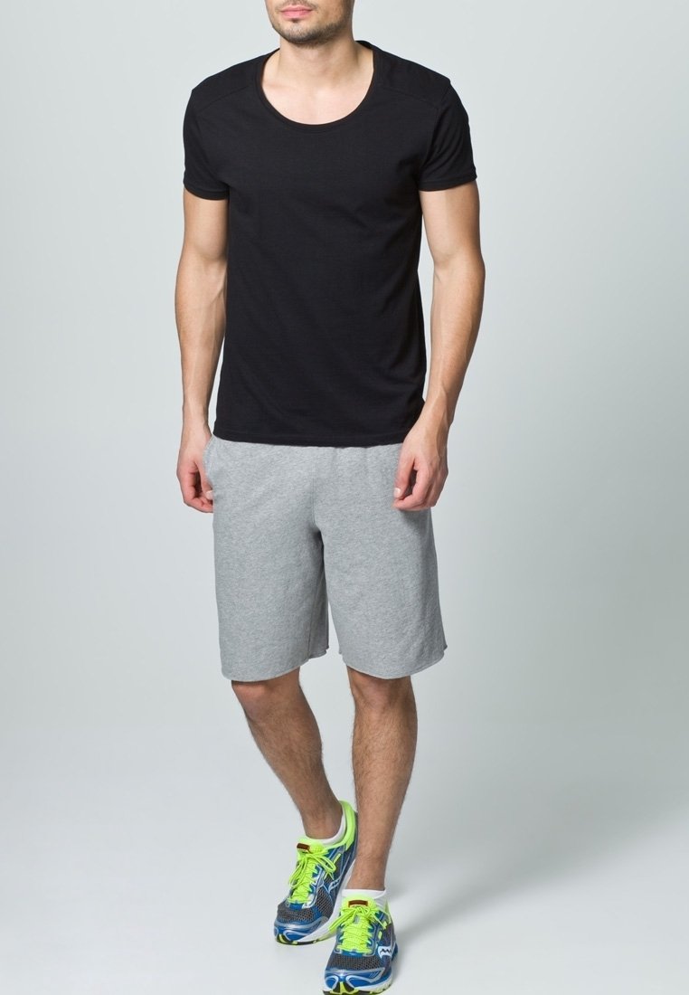 Černé tričko s krátkým rukávem v kombinaci se šedými sportovními šortkami a výraznými modrými teniskami se zelenými doplňky. Jednoduchý, neformální design.