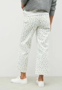 Bloemmotief, cropped broek in het wit met blauwe accenten, met een rechte snit en twee achterzakken, gecombineerd met witte sneakers.