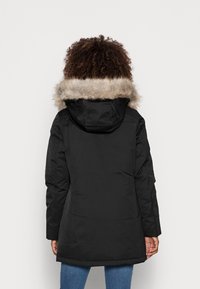Sort isoleret parka-jakke med en pelsforet hætte, der har en glat overflade og let buet kant. Enkelt, funktionelt design.
