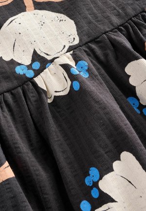 Zwarte stof met een gestructureerd oppervlak, gekenmerkt door grote witte bloemen en blauwe stippen, verzameld bij de taille in een vloeiende stijl.