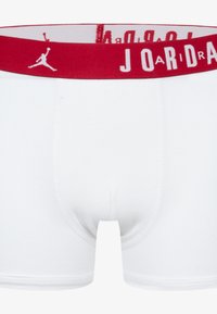 Weiße Boxer-Briefs mit einem roten elastischen Bund, der den Text und das Logo 'JORDAN' zeigt. Baumwollmaterial mit glatter Textur und figurbetontem Design.