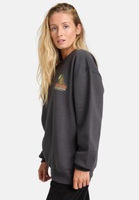 Grijze oversized sweatshirt met een ronde hals, voorzien van een kleurrijke cactusprint op de voorkant en geribde mouwen en onderkant.