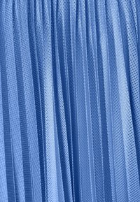 Primo piano di un tessuto blu plissettato con un motivo testurizzato di piccoli fori, che crea linee verticali e riflessi di luce.
