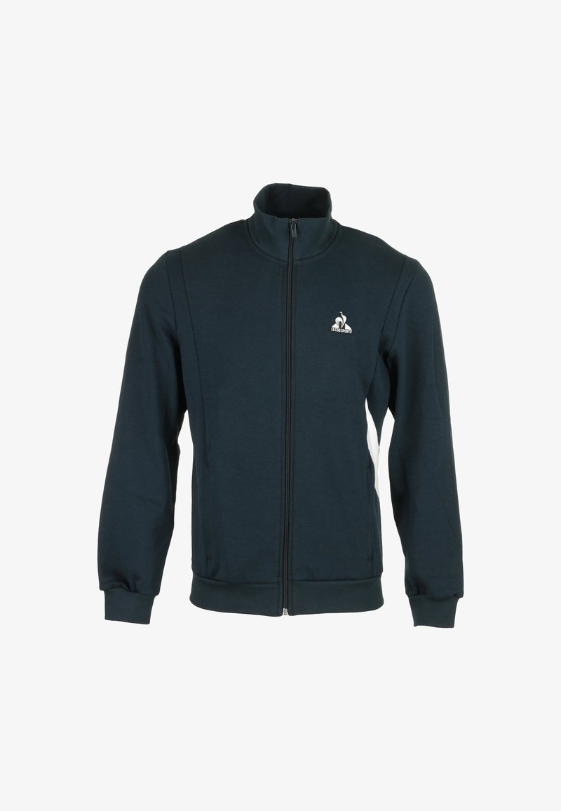 Chaqueta de cremallera verde oscuro con cuello alto, que presenta un logo en el lado izquierdo del pecho, puños elásticos y bolsillos laterales con detalles en blanco.