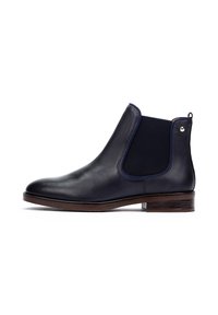 Bottines Chelsea en cuir noir avec une finition texturée, des panneaux latéraux élastiques et un talon en bois brun. Présente un subtil accent métallique près du talon.