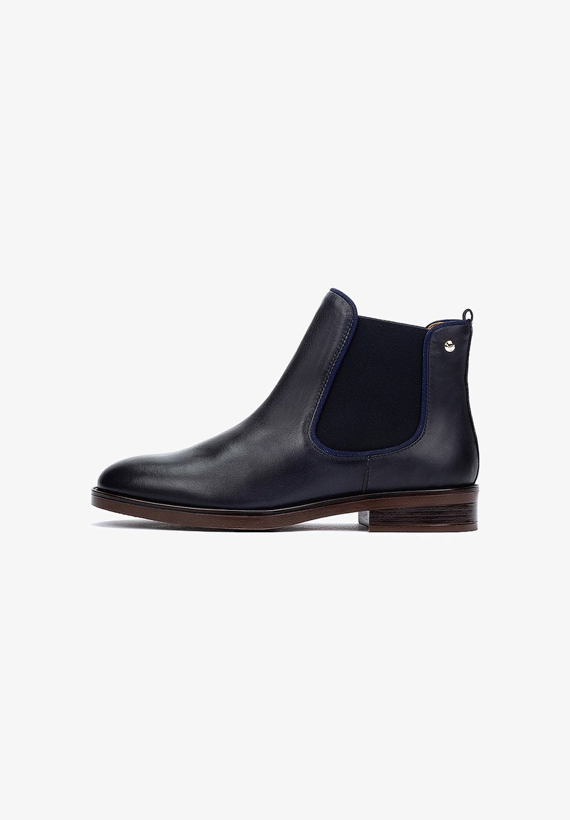 Bottines Chelsea en cuir noir avec une finition texturée, des panneaux latéraux élastiques et un talon en bois brun. Présente un subtil accent métallique près du talon.