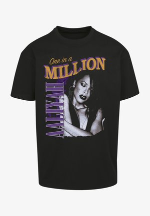 T-shirt di cotone nero con una stampa grafica del ritratto di una donna, con il testo "One in a Million" in viola e oro, posizionato verticalmente.