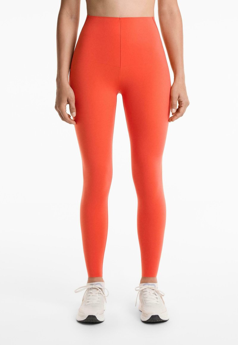High-waisted, strak aansluitende leggings in helder oranje, gemaakt van rekbare stof. Beschikt over een gladde textuur en heeft geen zichtbare branding.
