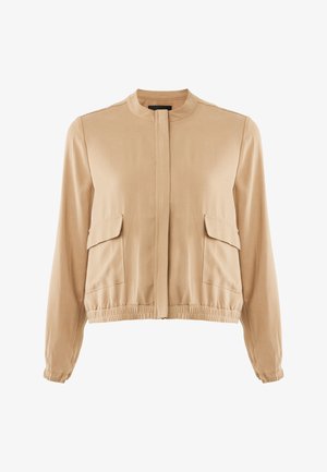 Beżowa lekka kurtka z okrągłym dekoltem, elastycznym dołem, dwoma naszywanymi kieszeniami z przodu oraz długimi rękawami zakończonymi elastycznymi mankietami. Gładka faktura tkaniny.