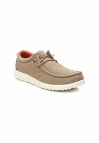 Zapato de lona beige con la punta redonda, forro naranja y suela de goma blanca en contraste. Presenta un diseño sencillo de cordones con un hardware mínimo.