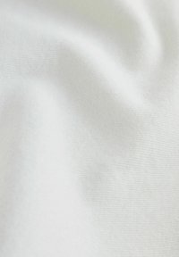 Tissu blanc doux avec de légères rides et une fine texture tissée visible en gros plan.