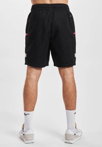 Schwarze Shorts mit elastischem Bund, seitlichen Taschen, rosa und beigen Akzenten sowie einem strukturierten Mesh-Einsatz an den Seiten.