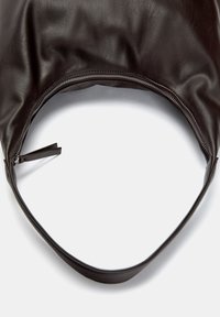Black leather bag with a soft, textured surface, curved shape, and a zipper opening at the top. Adjustable strap attached.