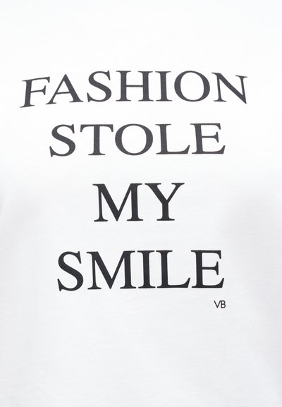 Λευκό ύφασμα με μαύρο κείμενο "FASHION STOLE MY SMILE" με κεφαλαία γράμματα και μικρά αρχικά "VB" κάτω δεξιά.