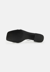 Sole di scarpa nera con tacco alto, con una finitura liscia, caratterizzata da una forma quadrata, texture rigata per la presa e una leggera curvatura sul bordo.