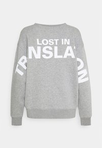 Sudadera gris con texto blanco "LOST IN TRANSLATION" en la espalda y la manga. Cuenta con un ajuste holgado y puños acanalados. Textura suave.