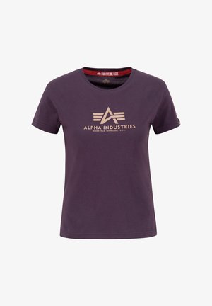 Fioletowa bawełniana koszulka z okrągłym dekoltem, z beżowym logo i napisem "ALPHA INDUSTRIES" umieszczonym centralnie na przodzie oraz metką w środku.