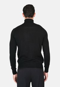 Maglione nero a collo alto lavorato a maglia con polsini e orlo a costine. Il materiale sembra morbido e aderente, presentando un design pulito e minimalista.