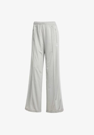 Světle šedé sportovní kalhoty s volným střihem, vyrobené ze hladkého syntetického materiálu. Obsahují elastický pas a boční kapsy na zip.