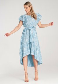 Jasnoniebieska, zwiewna sukienka z kwiatowymi wzorami, z falbankowymi rękawami, zaznaczoną talią i asymetrycznym hemem. Wyposażona w teksturowany materiał.