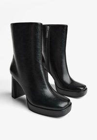 Botine negre din piele cu finisaj lucios, toc înalt și gros, vârfuri pătrate și fermoare laterale pentru acces facil.