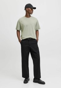 Tricou verde deschis cu guler rotund, croi lejer, mâneci scurte, asociat cu pantaloni negri cu picioare largi și pantofi negri. Căciula neagră purtată cu spatele.