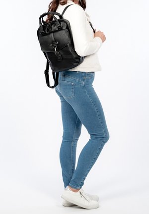 Zaino in pelle nera con pattina anteriore, hardware argentato e doppi manici superiori; spallacci regolabili e forma strutturata.