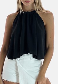 Schwarzes Neckholder-Top mit gerafftem Ausschnitt, fließendem Stoff und weicher Textur, kombiniert mit weißen Shorts. Verfügt über eine lockere, entspannte Passform.