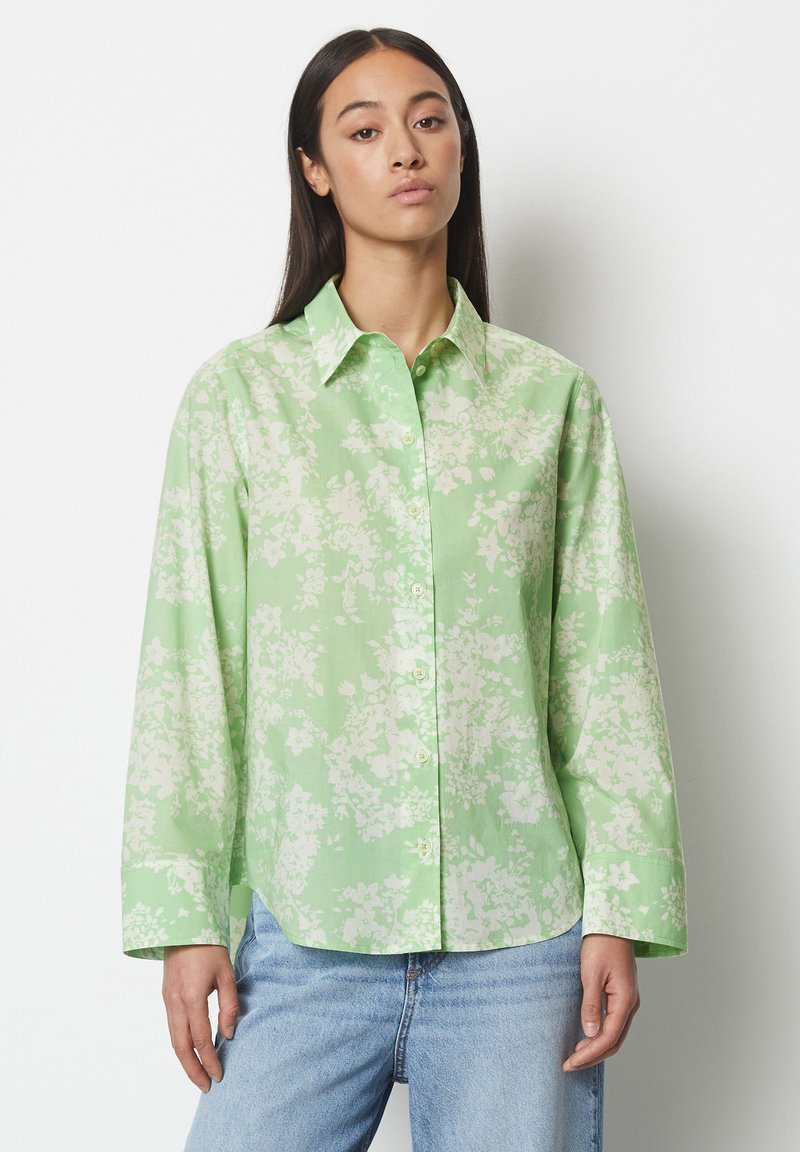 Camicia button-up verde chiaro con un motivo floreale in bianco. Presenta un colletto a punta e maniche lunghe, realizzata in un tessuto morbido.