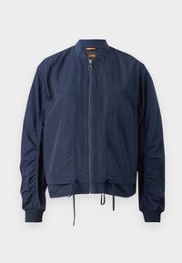 Veste bomber légère bleu marine avec fermeture éclair frontale, deux grandes poches avant, poignets côtelés et cordons ajustables à l'ourlet.