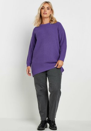 Maglione viola a maglia con un motivo testurizzato, con collo rotondo e maniche lunghe, abbinato a pantaloni grigi e stivali neri.