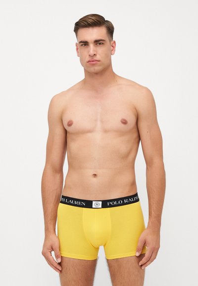 Sárga pamut boxer alsónadrág fekete elasztikus derékkal, amin a 'Polo Ralph Lauren' logó látható, testhezálló szabás és sima textúra jellemzi.