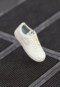 Bežni Nike Air Force 1 športni copat z perforiranim nosom, ravnimi vezalkami in teksturiranim logotipom Swoosh. Mehak material in oblazinjen notranji del.