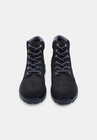 Stivaletti neri in suede, con punte rotonde, caratterizzati da lacci a contrasto, colli imbottiti e suole in gomma testurizzata per una maggiore aderenza.
