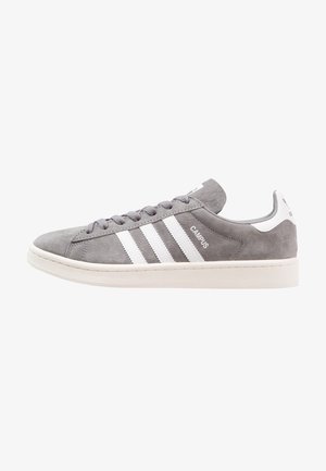 Baskets Adidas Campus en daim gris avec des bandes blanches, semelle blanche, lacets et languette au talon, montrées de profil latéral tourné vers la gauche.