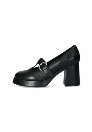 Scarpa con tacco alto in pelle nera, punta rotonda, design a T-strap, accentata da una fibbia circolare argentata e tacco spesso a blocco. Texture liscia.