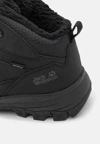 Zwarte wandelschoen met een gestructureerde bovenkant, versterkte stiksels, een kraag van faux bont en een robuuste zool met multidirectionele profiel.