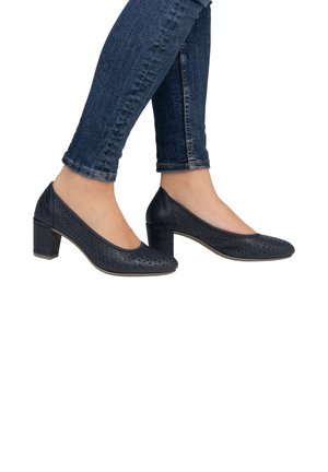 Dunkelblaue, durchbrochene Lederabsätze mit runder Spitze und klobigem Absatz. Getragen mit engen, dunklen Jeans, die das Design des Schuhs zur Geltung bringen.