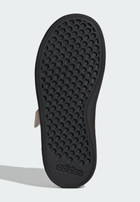 Semelle de chaussure en caoutchouc noir présentant une texture en nid d'abeille, avec le logo "adidas" embossé en bas. Bords lisses et design structuré.