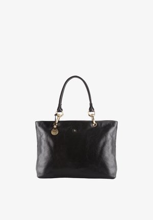 Borsa tote in pelle nera con due manici, hardware color oro e un ciondolo rotondo in oro attaccato vicino a un manico.