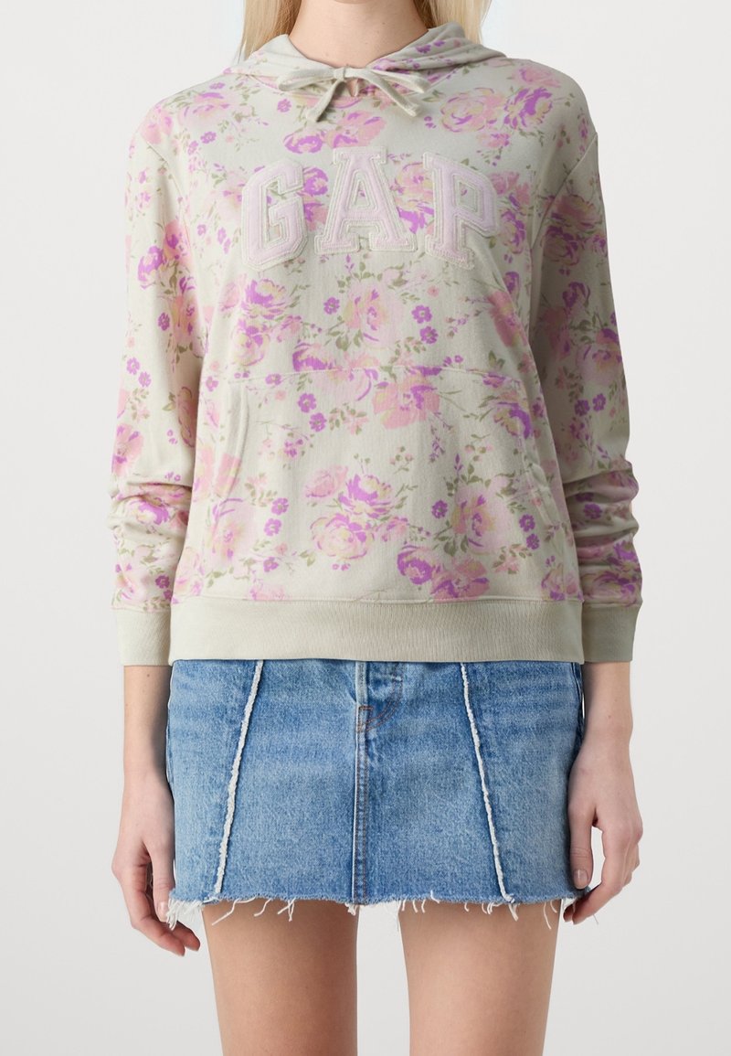 Lichtgrijze hoodie met bloemmotief en geborduurde 'GAP' in geschreven lettertype, voorzien van een capuchon met trekkoord en ribbelboorden, gecombineerd met een denim minirok.