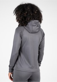 Grijze hoodie met lange mouwen en een aansluitend ontwerp, voorzien van een trekkoordkap. Gladde stoftextuur en platgestikte naden voor comfort.