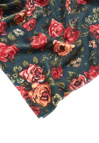 Bloemenstof met grote rode en oranje rozen op een donkerblauwe achtergrond, met groene bladeren en kleine bloemen; zachte textuur, licht rafelende rand.