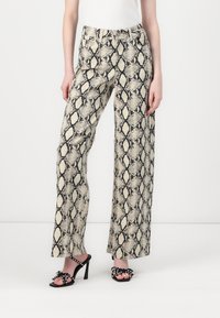 Pantalones de pierna ancha con un estampado de serpiente, en tonos de crema y negro. Confeccionados en una tela suave, detallados con una cinturilla ajustada.