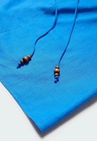 Modrá tkanina s hladkým povrchem, která obsahuje dvě šňůrky s dřevěnými korálky na koncích. Design je jednoduchý a moderní.