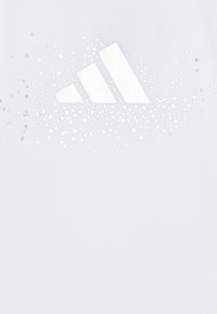 Biela športová košeľa s veľkým, reflexným logom Adidas, okolo ktorého je bodkovaný vzor strieborných bodiek a hviezd.