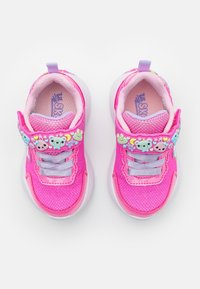 Jasnoróżowe dziecięce trampki z fioletowymi sznurówkami i zdobionymi paskami z kolorowymi kształtami misiów i serc, widok z góry.