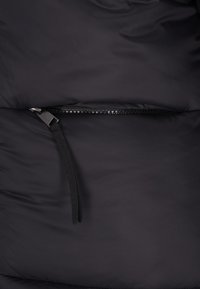 Schwarzer Stoff mit einem horizontalen, teilweise geöffneten schwarzen Reißverschluss und einem schwarzen Stofflaschen-Zipper-Schieber.