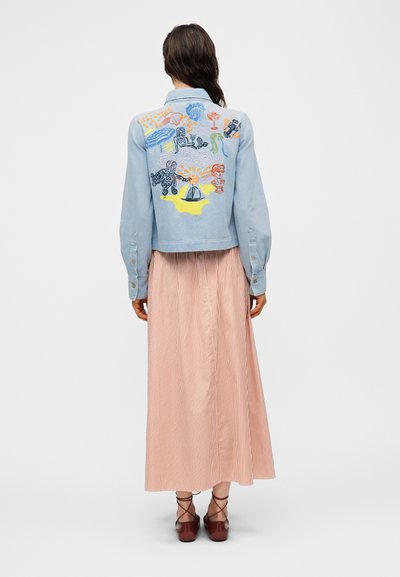 Τζιν μπουφάν σε ανοιχτό γαλάζιο με πολύχρωμα κεντημένα σχέδια στην πλάτη. Συνδυάζεται με μακριά, ριγέ, παστέλ φούστα και καφέ παπούτσια.