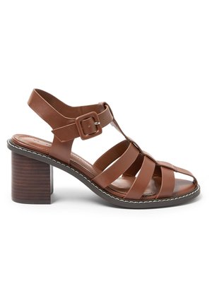 Sandale à talon marron en cuir avec talon bloc, bout ouvert, multiples brides et une grande boucle de fermeture sur la sangle de cheville.